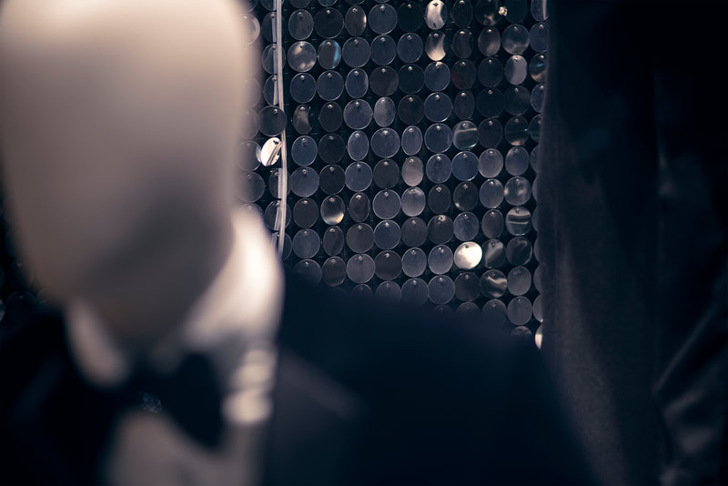 A black sequin wall in the background behind a mannequin wearing a suit.
