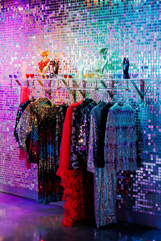 A shelf and clothes hanger mounted on top of the sequin wall.