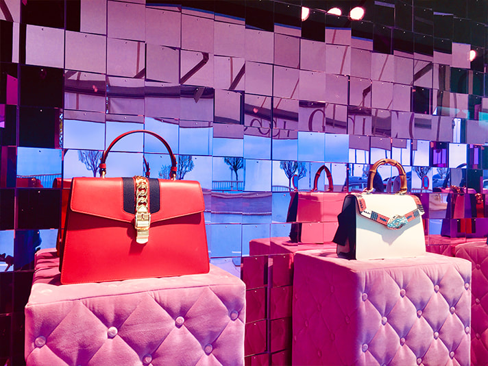 A photograph of two fashion brand bags with shimmerwall visual merchandising background.