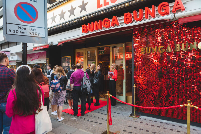 Customers waiting outside a store with the red sequin backdrop.