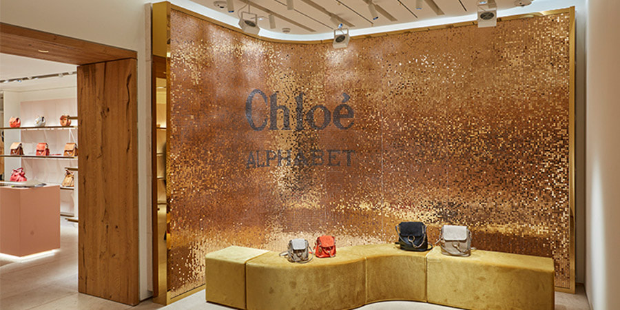 A large Shimmerwall sequin wall backdrop behind a luxury bag collection